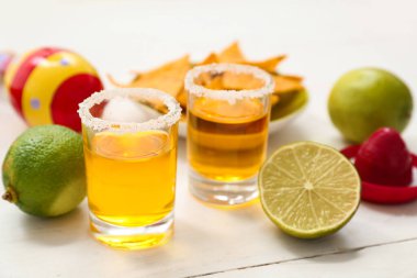 Beyaz arka planda tekila, limon ve marakas, yakın plan.