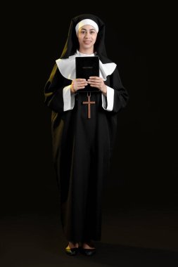 Siyah arka planda İncil 'i olan genç rahibe.