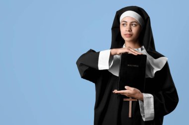 Mavi arka planda İncil 'i olan genç rahibe.