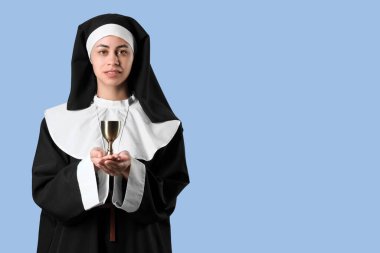 Mavi arka planda kadehi olan genç rahibe.
