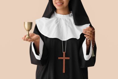 Bej arka planda tespih ve kadehli genç rahibe.