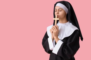 Pembe arka planda haç çizen genç rahibe