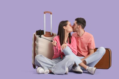 Güzel, genç, mutlu, bavullu turistler mor arka planda selfie çekiyorlar.