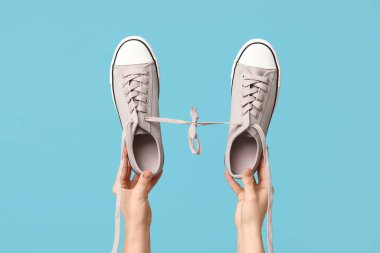 Mavi arka planda şık spor ayakkabıları olan kadın elleri