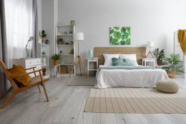 Yatak odasının içi yumuşak yatak, lambalar, raf üniteleri ve komodinlerle dolu.