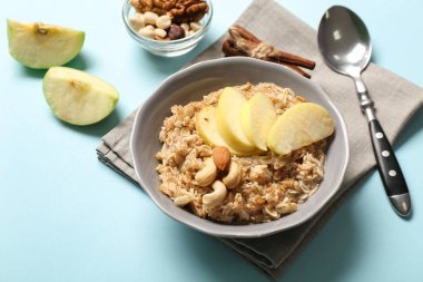 Lezzetli yulaf ezmeli kase, dilimlenmiş elma ve fındıklı mavi arka plan