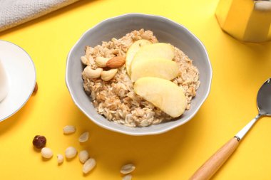 Sarı arka planda dilimlenmiş elma ve fındıklı lezzetli yulaf ezmesi.