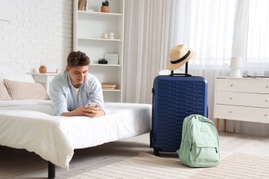 Otel odasındaki yatakta cep telefonu kullanan erkek turist.