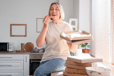 Mutfakta lezzetli pizzası olan güzel bir kadın. Aşırı yeme kavramı