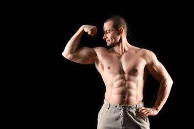Siyah arka planda kol kasları gösteren erkek vücut geliştirici.