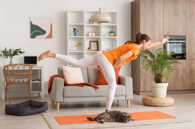 Sevimli kedisi olan hamile bir kadın evde yoga yapıyor.