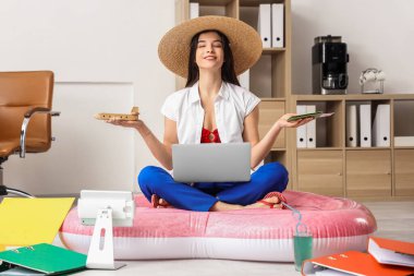 Ahşap uçakla, pasaportuyla ve laptopuyla ofiste meditasyon yapan genç bir iş kadını. Yaz tatili kavramı