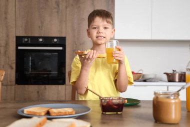 Mutfakta tost ve meyve suyu olan şirin bir çocuk.