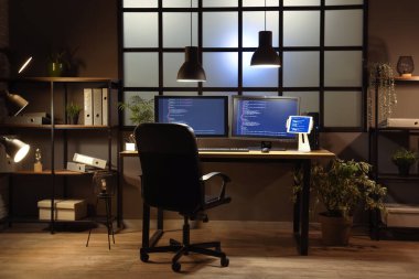 Geceleri programcı işyeri ve raf üniteleri olan karanlık ofisin içinde.