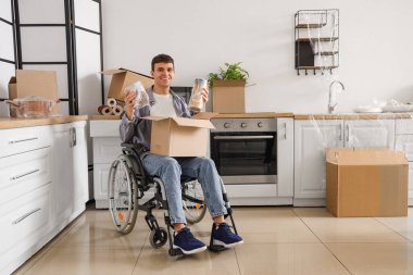 Evdeki tamirat sırasında tekerlekli sandalyedeki genç adam yiyecek dolu kavanozlar hazırlıyor.