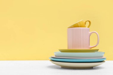 Sarı arkaplana karşı masada temiz bardak ve tabaklar