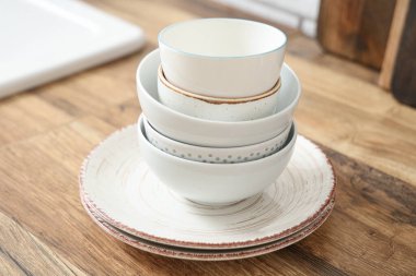 Ahşap masada beyaz, temiz sofra takımı yığını