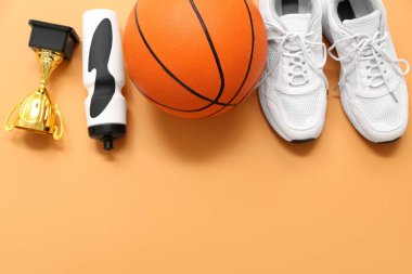 Kupa, spor şişesi, basketbol ve turuncu arka planda beyaz spor ayakkabıları.