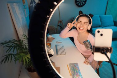 Kulaklıklı kız öğrenci akşam evde video oyunu oynuyor.