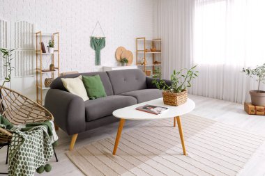 Kahve masası ve kanepenin üzerinde bambu sapları olan modern oturma odasının içi aydınlık.