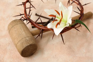 Wooden hammer with crown of thorns, lily and nails on light background clipart
