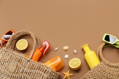 Güneş kremi ve kahverengi arka planda plaj aksesuarları olan şişeler.