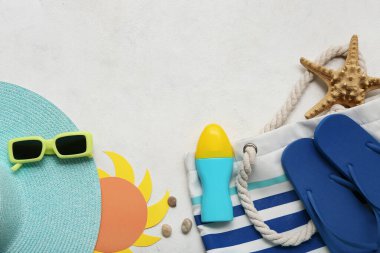Beyaz arka planda güneş koruma kremi ve plaj aksesuarları.