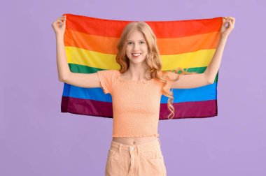 Mor arka planda LGBT bayrağı olan güzel, genç ve mutlu bir kadın.