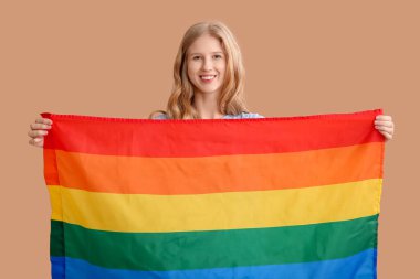 Bej arka planda LGBT bayrağı olan güzel, genç ve mutlu bir kadın.