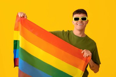 Sarı arka planda LGBT bayrağı olan yakışıklı genç adam.