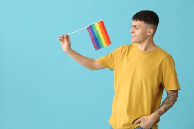 Mavi arka planda LGBT bayrakları olan yakışıklı genç adam.
