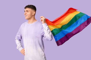 Mor arka planda LGBT bayrağı olan yakışıklı genç adam.
