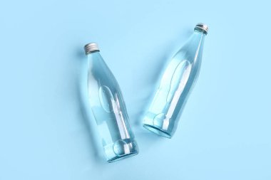 Mavi zemin üzerinde cam temiz su şişeleri
