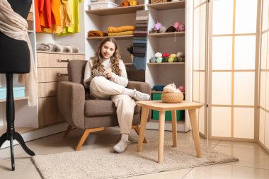 Atölyedeki koltuğa iğnelerle örgü ören kadın terzi.