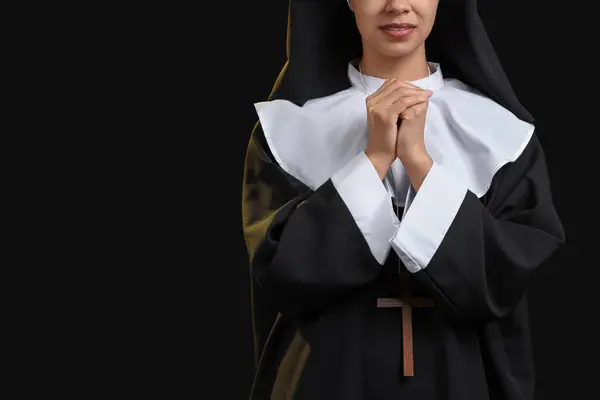 stock image Praying young nun on black background