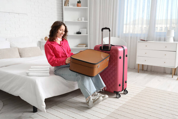 Женщина-туристка с чемоданами, сидящая в номере отеля