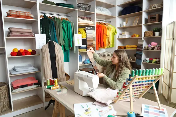 Stock image Female tailor with fabric samples working at table in atelier