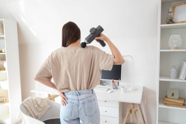 Ofiste boynuna perküsyon masajıyla masaj yapan genç bir kadın.