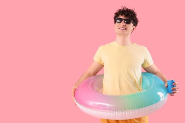 Pembe arka planda şişirilebilir yüzüğü olan yakışıklı genç adam.