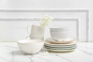 Beyaz duvarın yanındaki mermer masada çiçekli güzel sofra takımı.