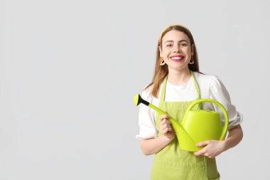 Gri arka planda sulama kutusu olan mutlu genç bir kadın.