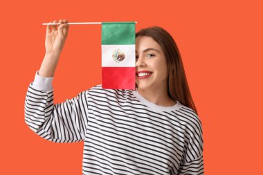 Turuncu arka planda Meksika bayrağı olan mutlu genç bir kadın.
