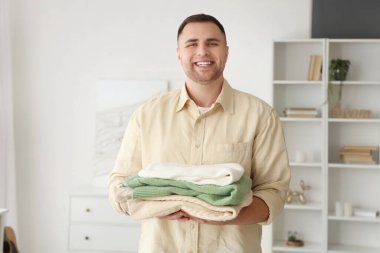 Evde bir yığın elbisesi olan genç bir adam.