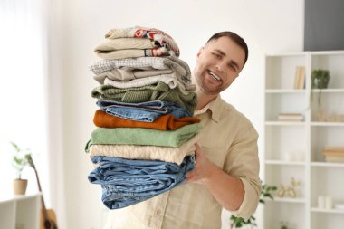 Evde bir yığın elbisesi olan genç bir adam.