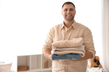 Evde bir yığın elbisesi olan genç bir adam.