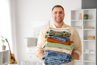 Evde bir yığın elbisesi olan genç bir adam.