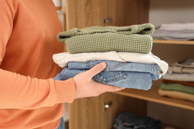 Genç adam evdeki dolaba kıyafet yığını koyuyor, yakın plan.