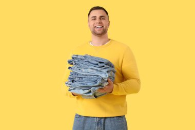 Sarı arka planda kot pantolonlu genç adam.