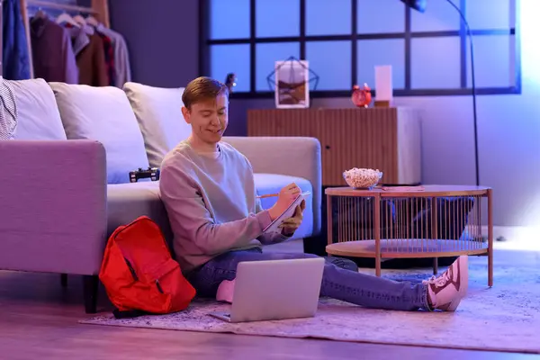 Stock image Male student with notebook studying online at home in evening