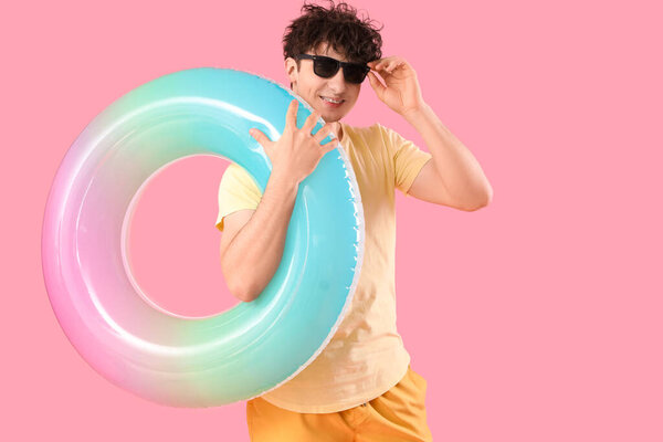 Красивый молодой счастливый мужчина с надувным кольцом на розовом фоне